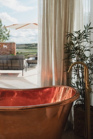 The en suite bathroom features a deep copper bath with a garden view